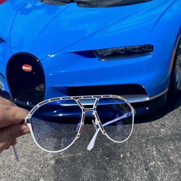 EYECON 87 premium frame held in front of Bugatti supercar